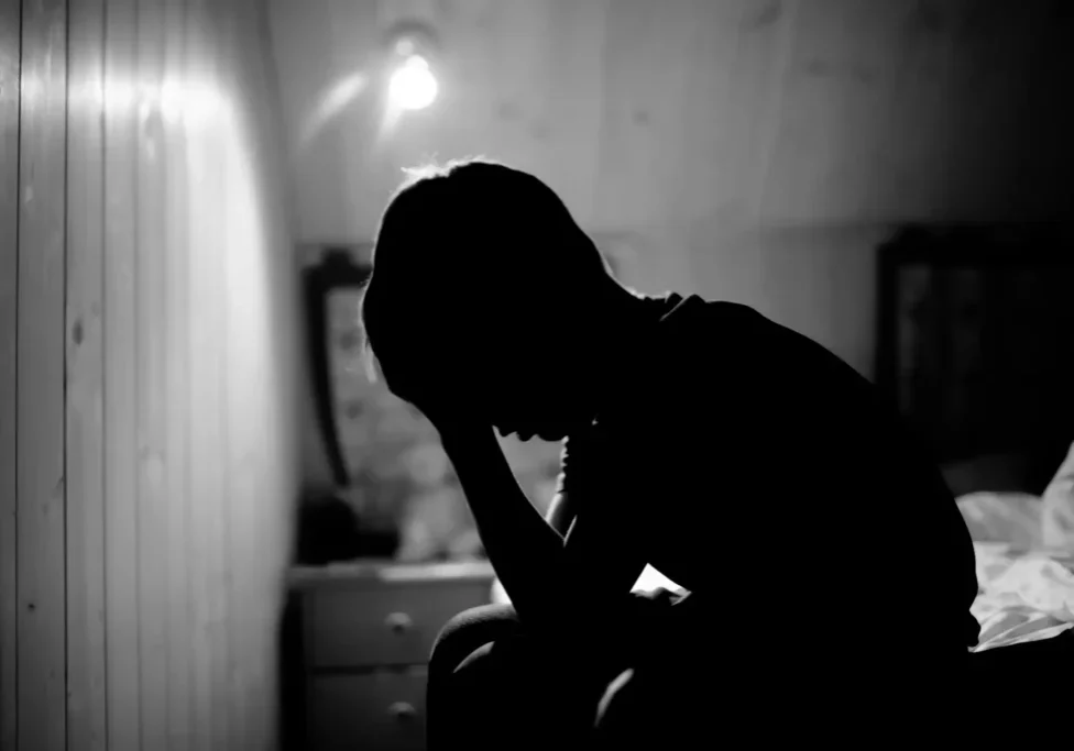 Silhouette of person sitting in dimly lit room.